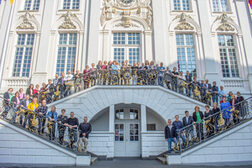 Many people stand on the steps in front of the Old Town Hall and smile at the camera.